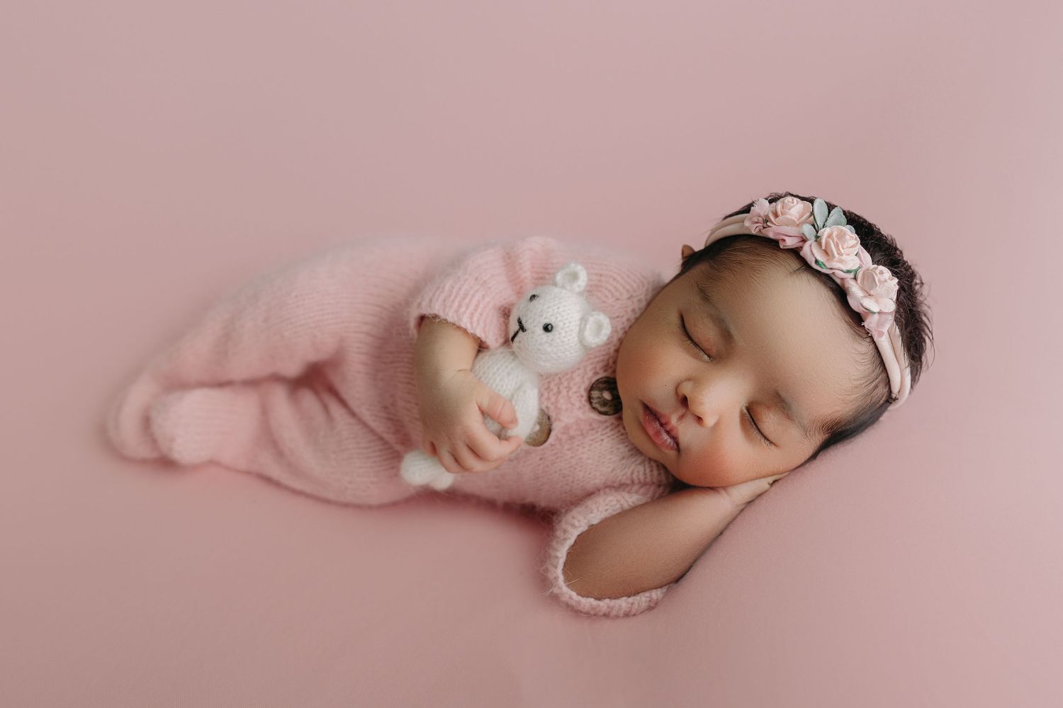 Sleeping newborn baby girl in pink outfit with teddy bear during Tampa newborn photography session