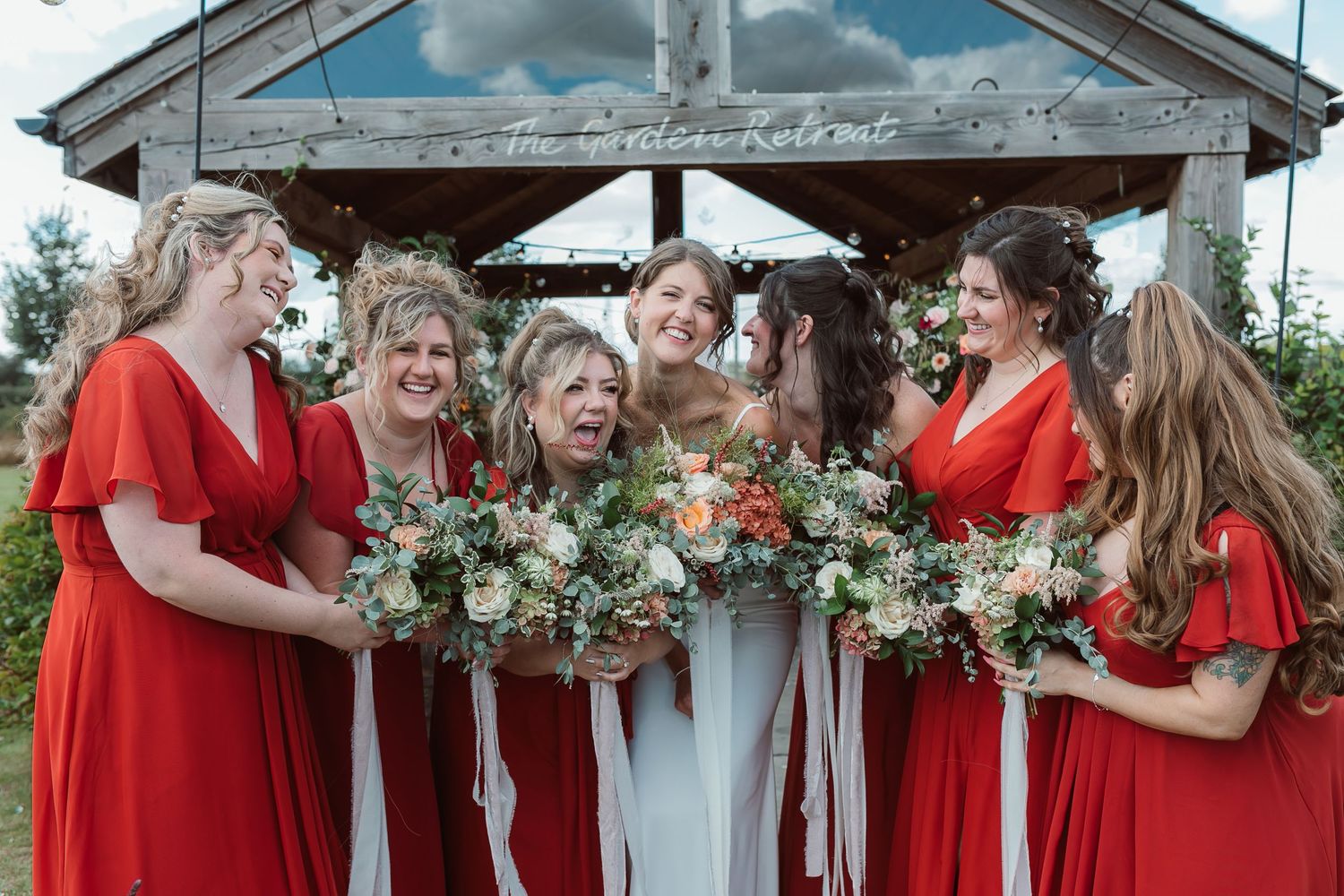 Bridesmaids in red dresses sharing joyful moments under a wooden pergola. Photographer. Hull. East Yorkshire. Photography