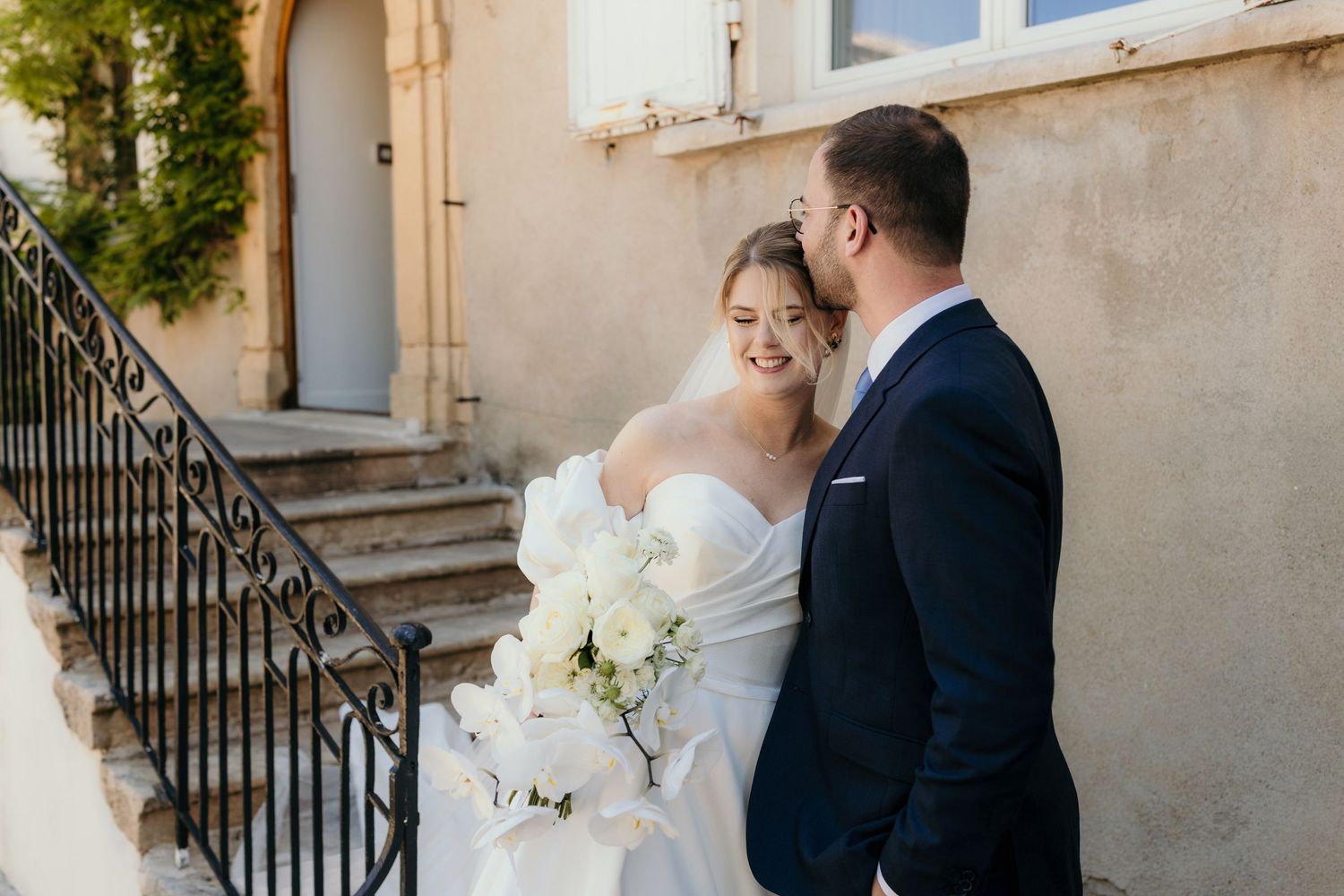 A romantic black and white wedding photograph showing a tender embrace in a natural outdoor setting.