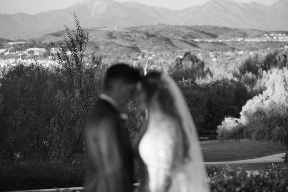 Black and white silhouette of wedding couple against mountain landscape backdrop.
