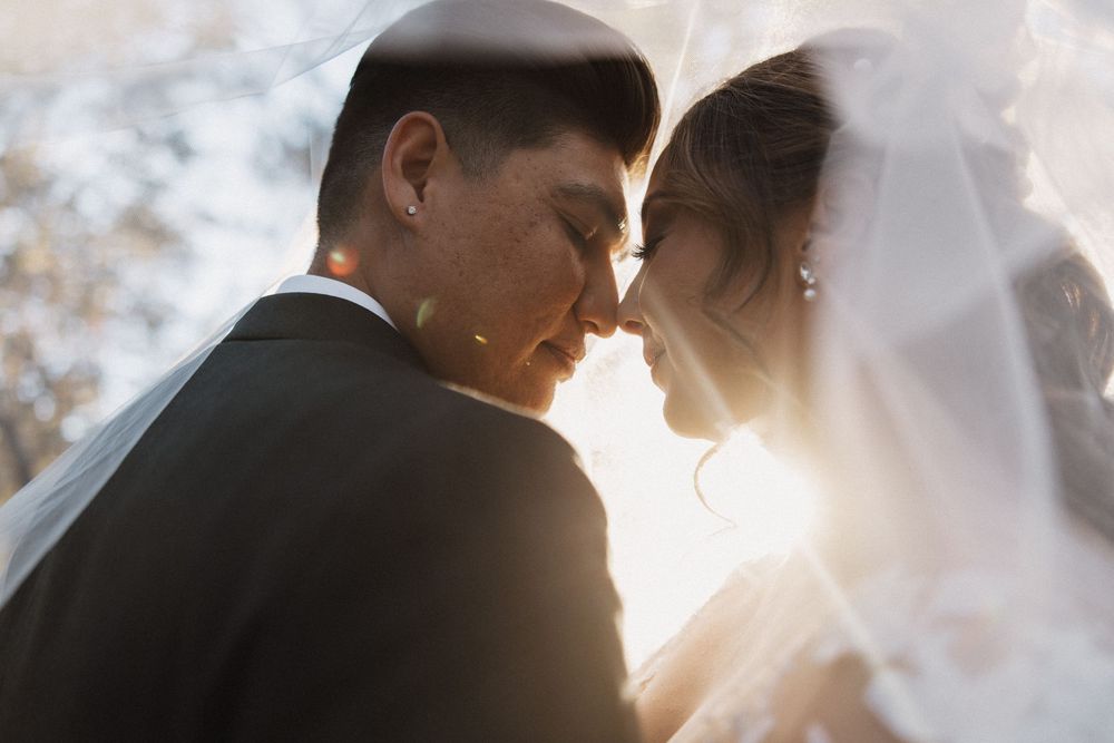 Dramatic silhouette of a wedding couple embracing against bright sunlight creating a romantic backlit effect.