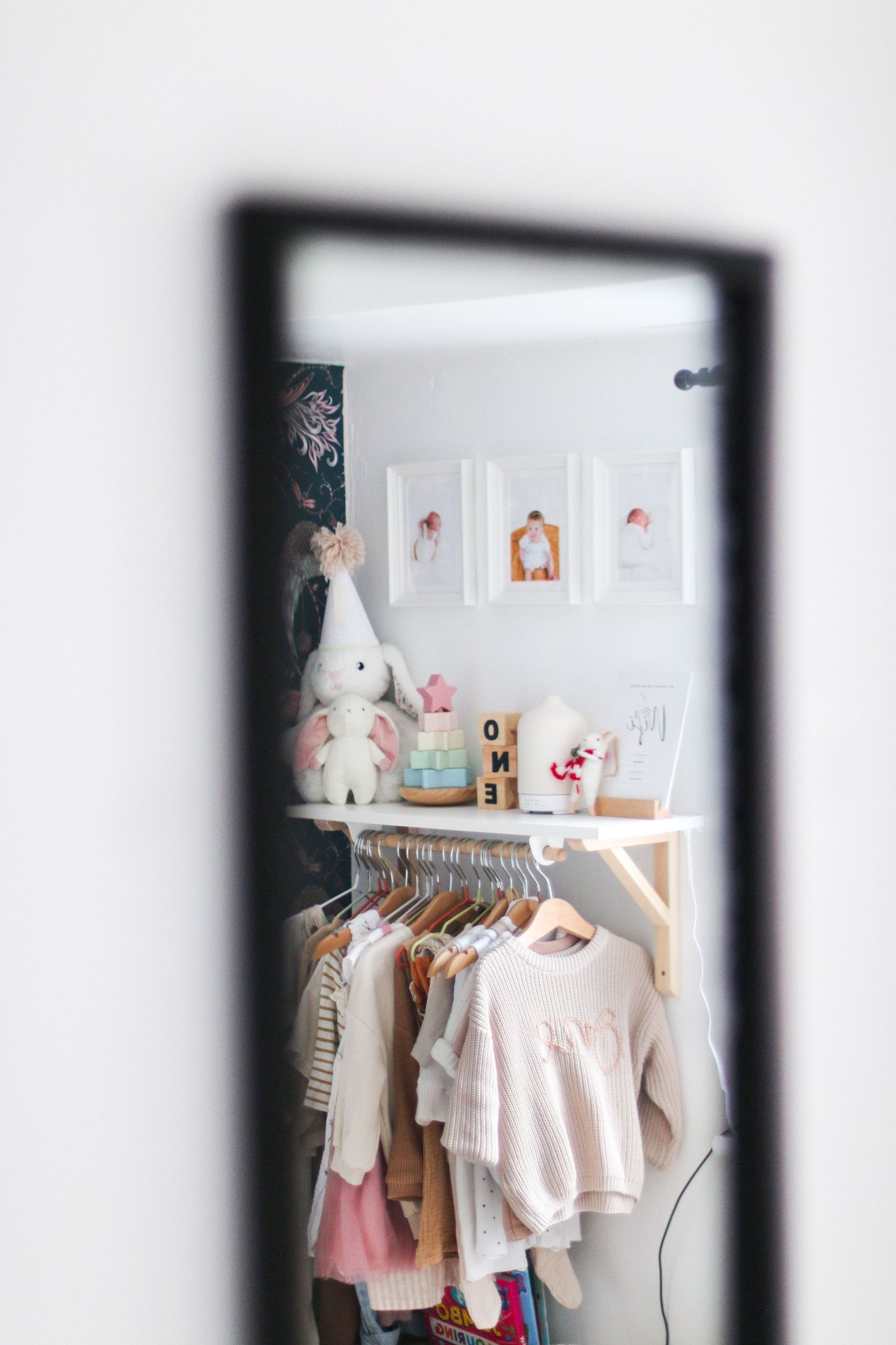 White and pastel baby clothes hanging on display in Nottingham photography studio with decorative wall art and plush toys.