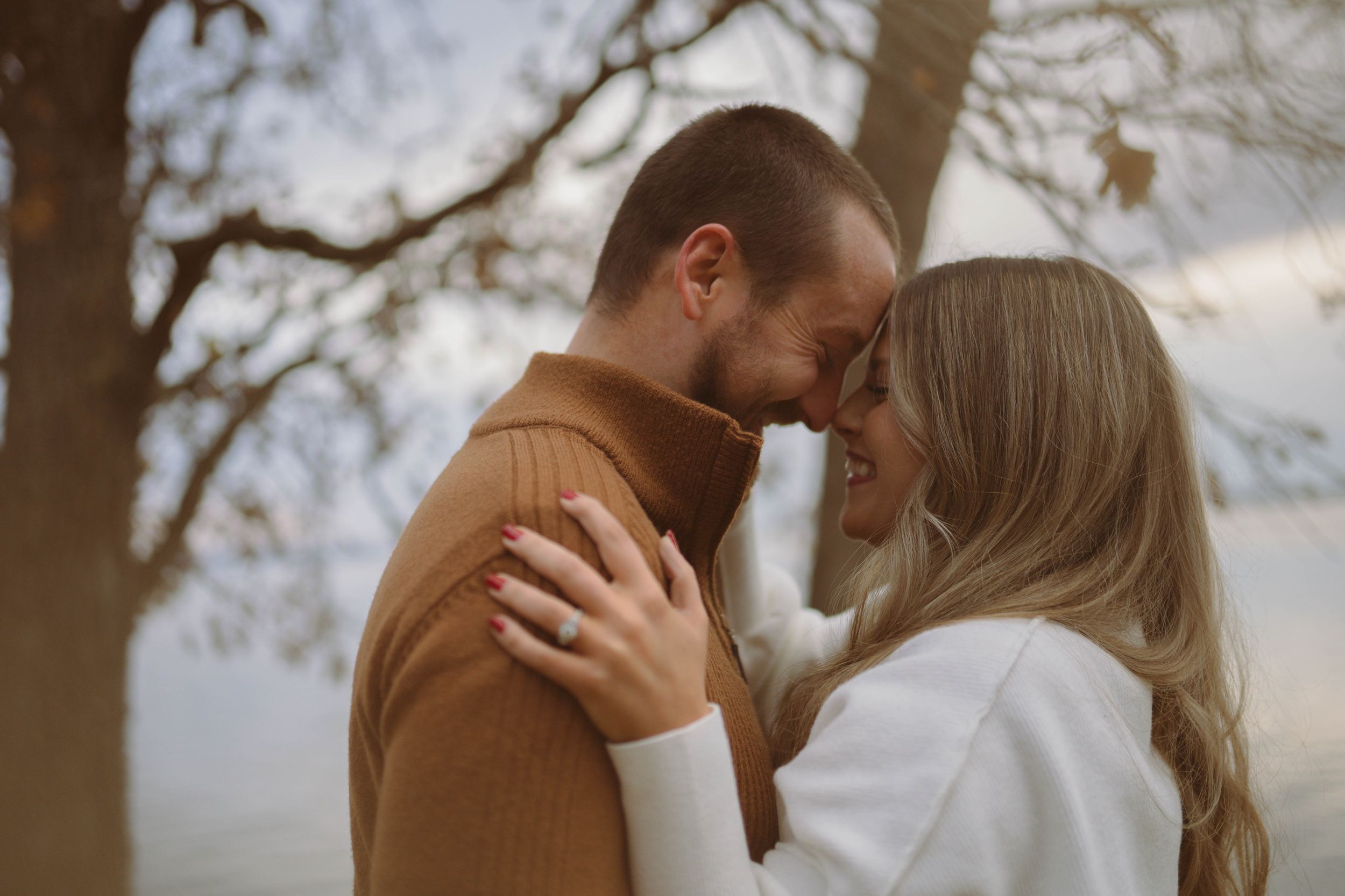 Tender moment between couple wearing cozy sweaters outdoors.