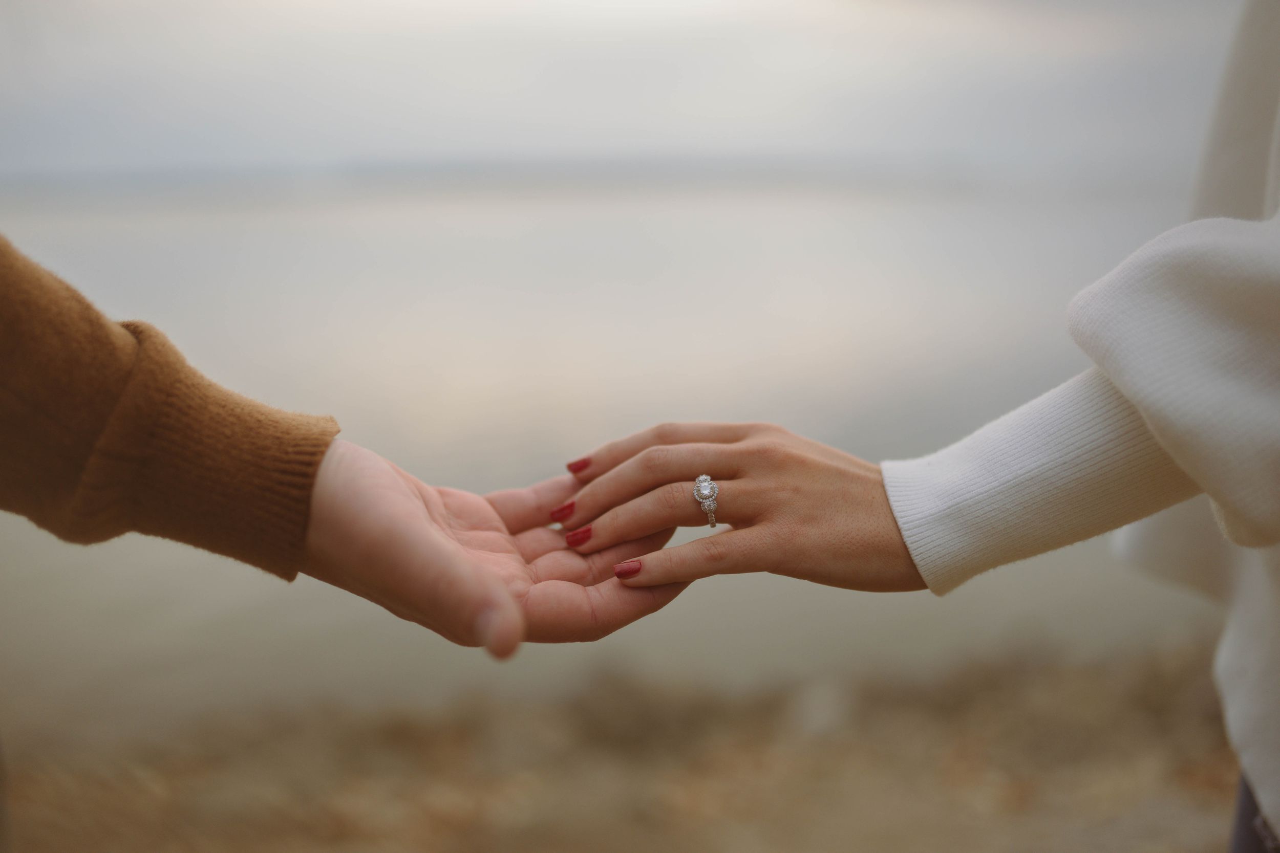 Hands reaching towards each other against a soft, blurred background.