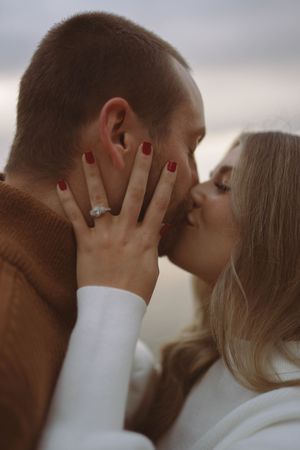 Tender moment between couple with engagement ring visible in soft lighting.