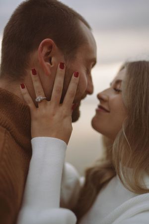 Intimate portrait of couple in contrasting brown and white sweaters during sunset.