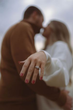 Close-up detail of engagement ring and red nails during intimate couple moment.