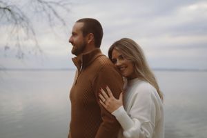 A tender moment between a couple against a waterfront backdrop.