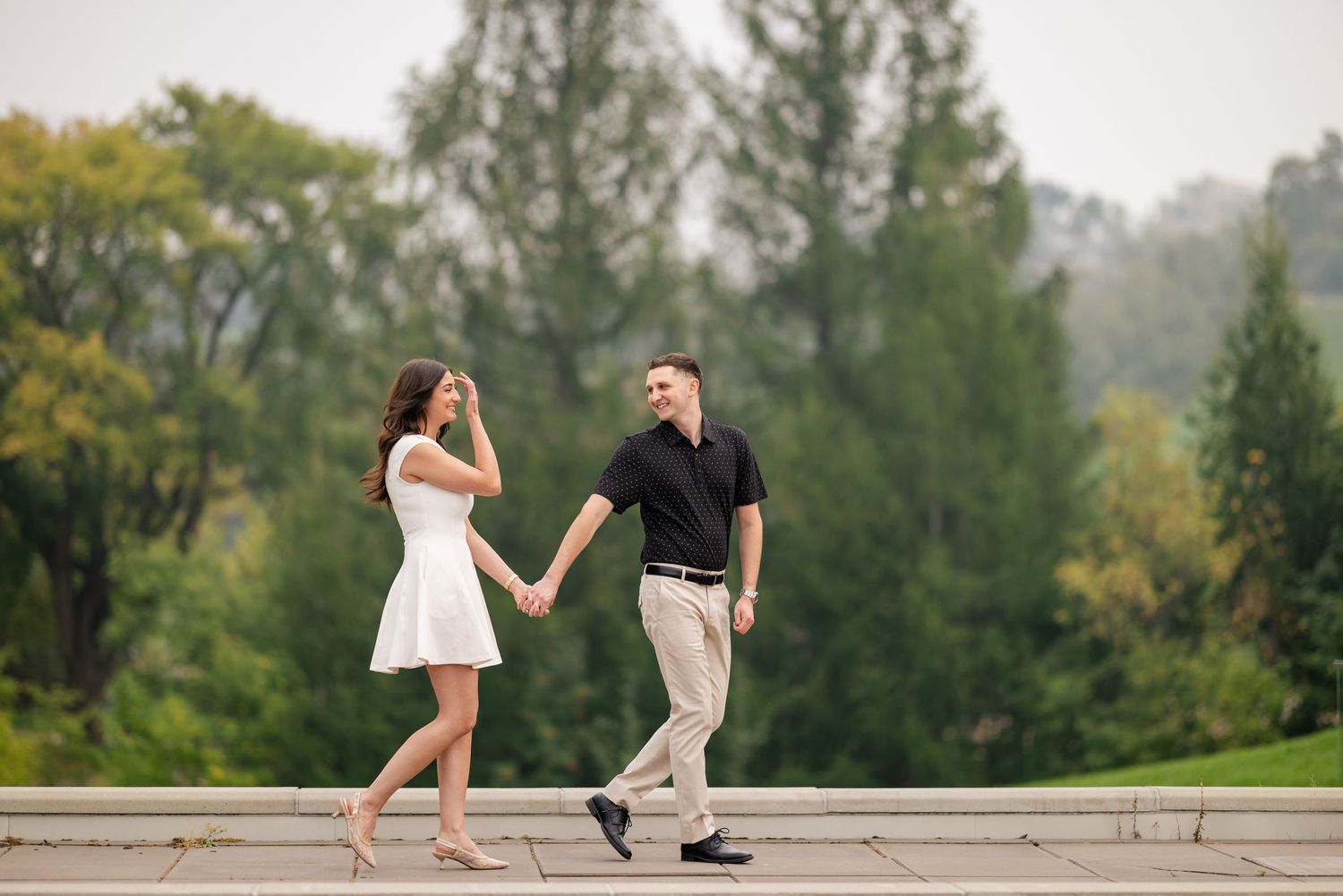Couple walking hand in hand along a garden path with ivy-covered walls.