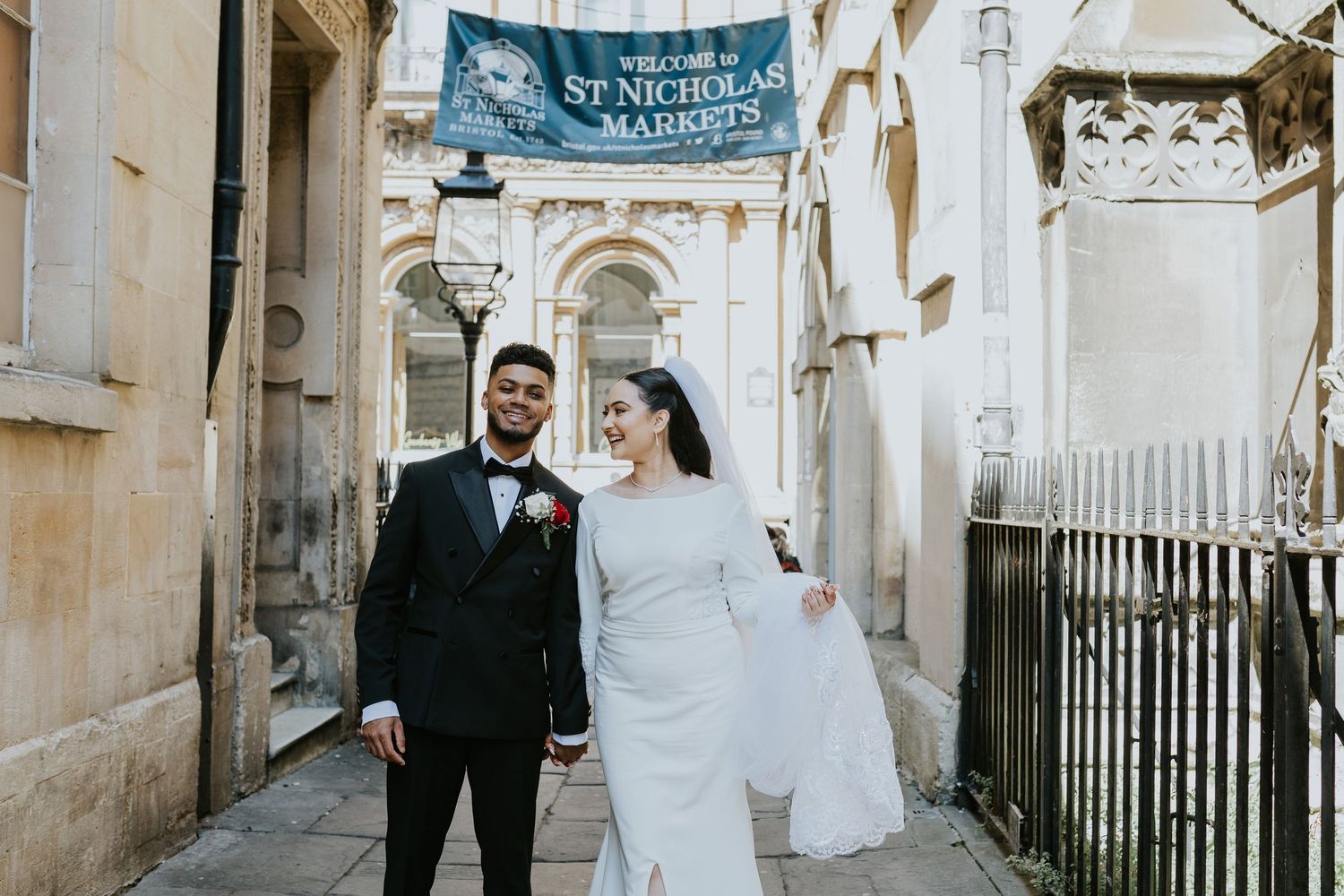 A happy couple walks through narrow stone streets during their wedding celebration in Italy.