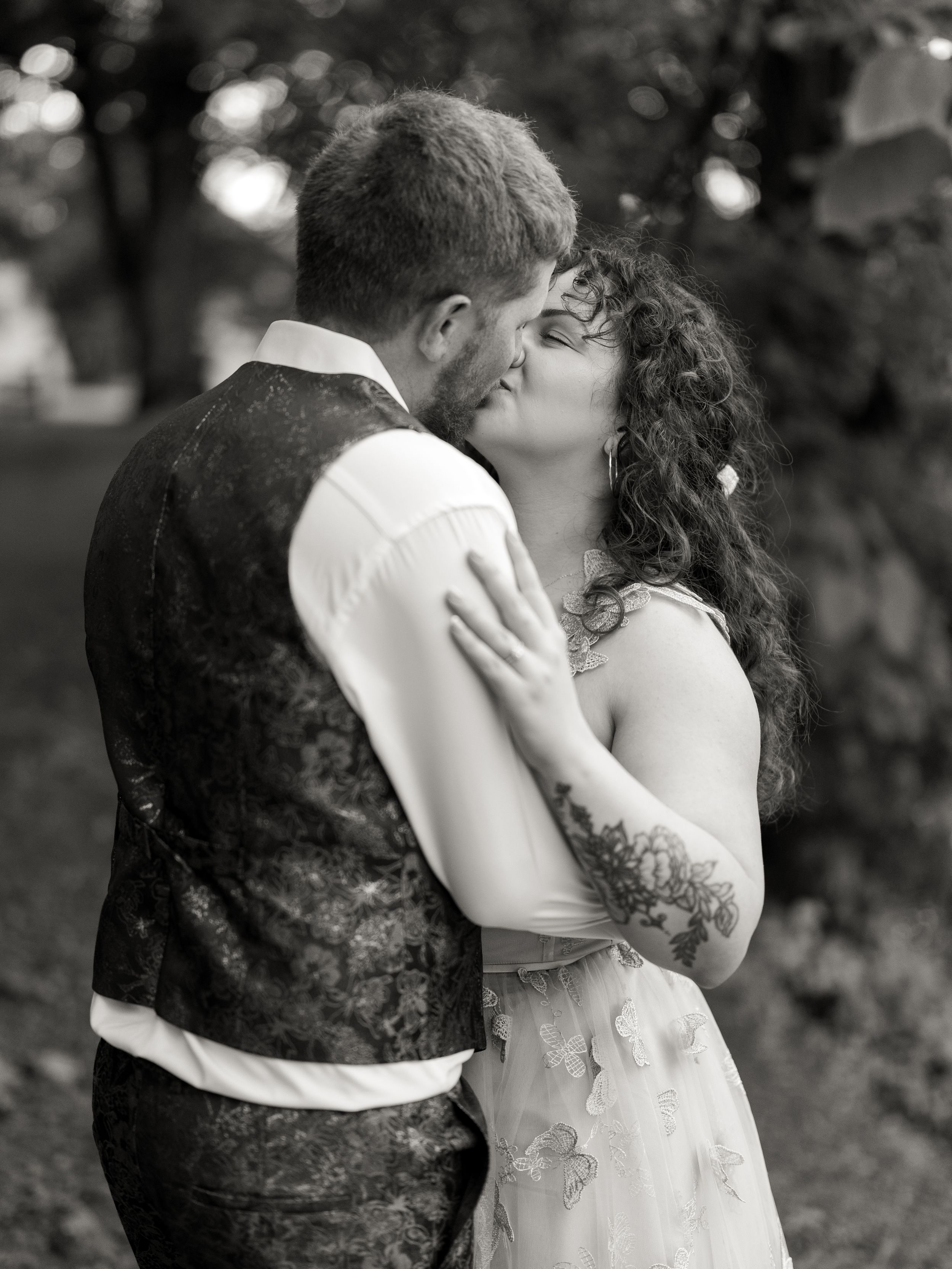 An intimate moment captured in black and white showing a couple in vintage-inspired formal wear embracing.