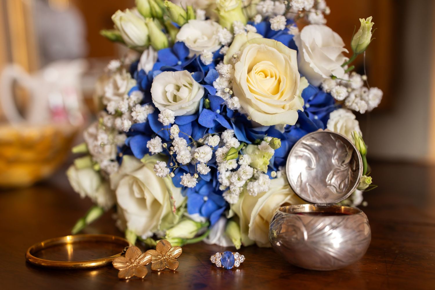 photographie de bouquet de fleurs de mariage bleu avec des boucles d'oreilles, une bague et une boite de rangement rose