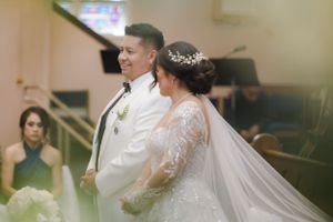 Intimate moment during Catholic wedding ceremony at decorated church altar.