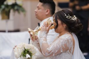 Close-up view of wedding ceremony participants in formal attire at church altar.
