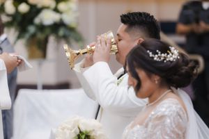 Wedding ceremony participants exchanging vows at decorated church altar.