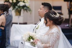 Traditional Catholic wedding ceremony with priest and couple at ornate church altar.