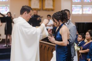 Church wedding ceremony with attendants in navy blue dresses and white robes.