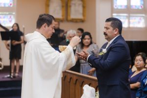 A priest and groom exchange rings during a traditional Catholic church wedding ceremony.