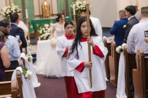 Church wedding ceremony with altar servers and decorative floral arrangements.