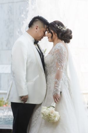 A romantic wedding portrait of a couple in white attire sharing an intimate moment.