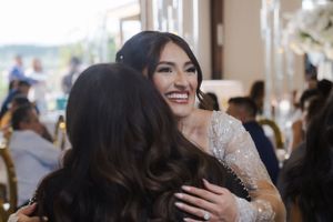 A joyful embrace between two wedding guests sharing a heartfelt moment at a reception celebration.