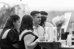 Black and white photo of guests ordering drinks at a wedding reception bar.