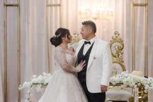 A romantic moment between newlyweds in their wedding attire against an elegant backdrop.