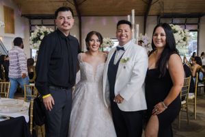 Wedding party gathering for photos in rustic indoor venue with wooden beams.