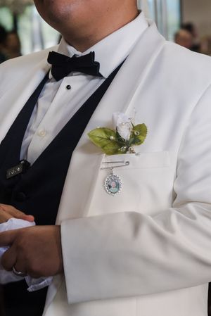 Close-up of formal white tuxedo jackets with black bow ties and floral boutonnieres.