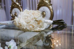 Elegant white rose bouquet display on reflective surface with soft lighting.
