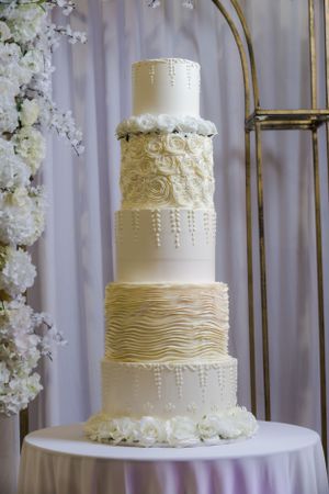 Elegant three-tier white wedding cake with textured frosting and pearl details.