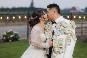 A romantic outdoor wedding photo with string lights and mountains creating an elegant backdrop.