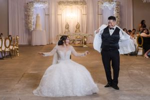Wedding couple dancing together in an elegant ballroom with ornate decor and lighting.