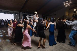 Festive crowd dancing and mingling at a formal event in a spacious indoor venue.