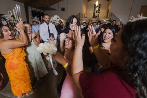 Wedding reception guests dancing and celebrating in a festively lit indoor venue.