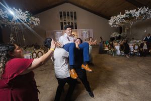 Wedding guests dancing under dramatic lighting at indoor reception venue.
