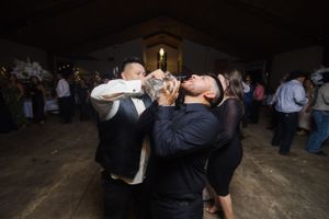 Wedding guests dancing in dark reception hall with ambient lighting.
