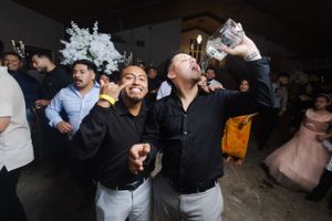 Wedding guests dancing and celebrating enthusiastically on dark dance floor.
