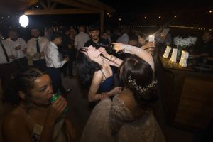 Wedding reception guests dancing and celebrating at night under string lights.