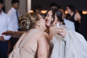 Emotional embrace between bride and wedding guest during reception celebration.
