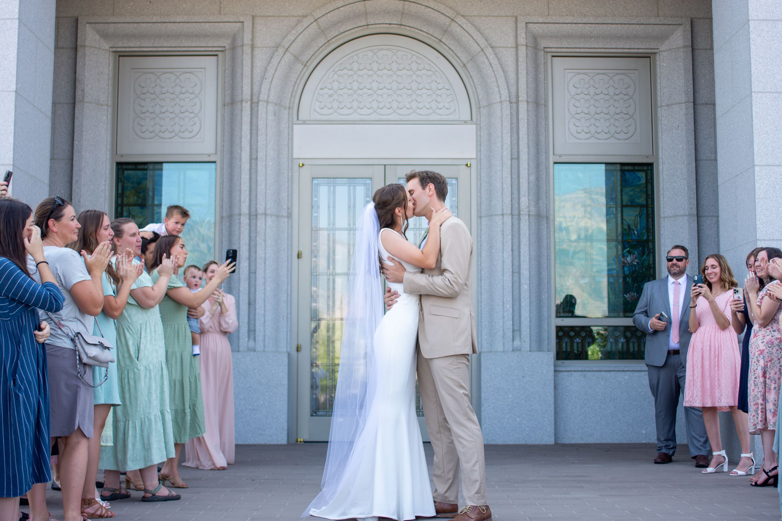 Bride and groom kiss in front of Orem Utah temple.