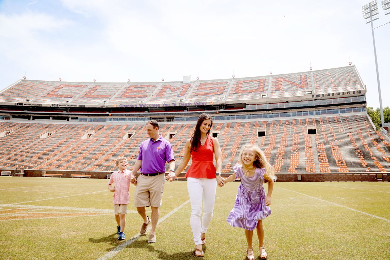 Family walking together on a football field inside a large empty stadium.