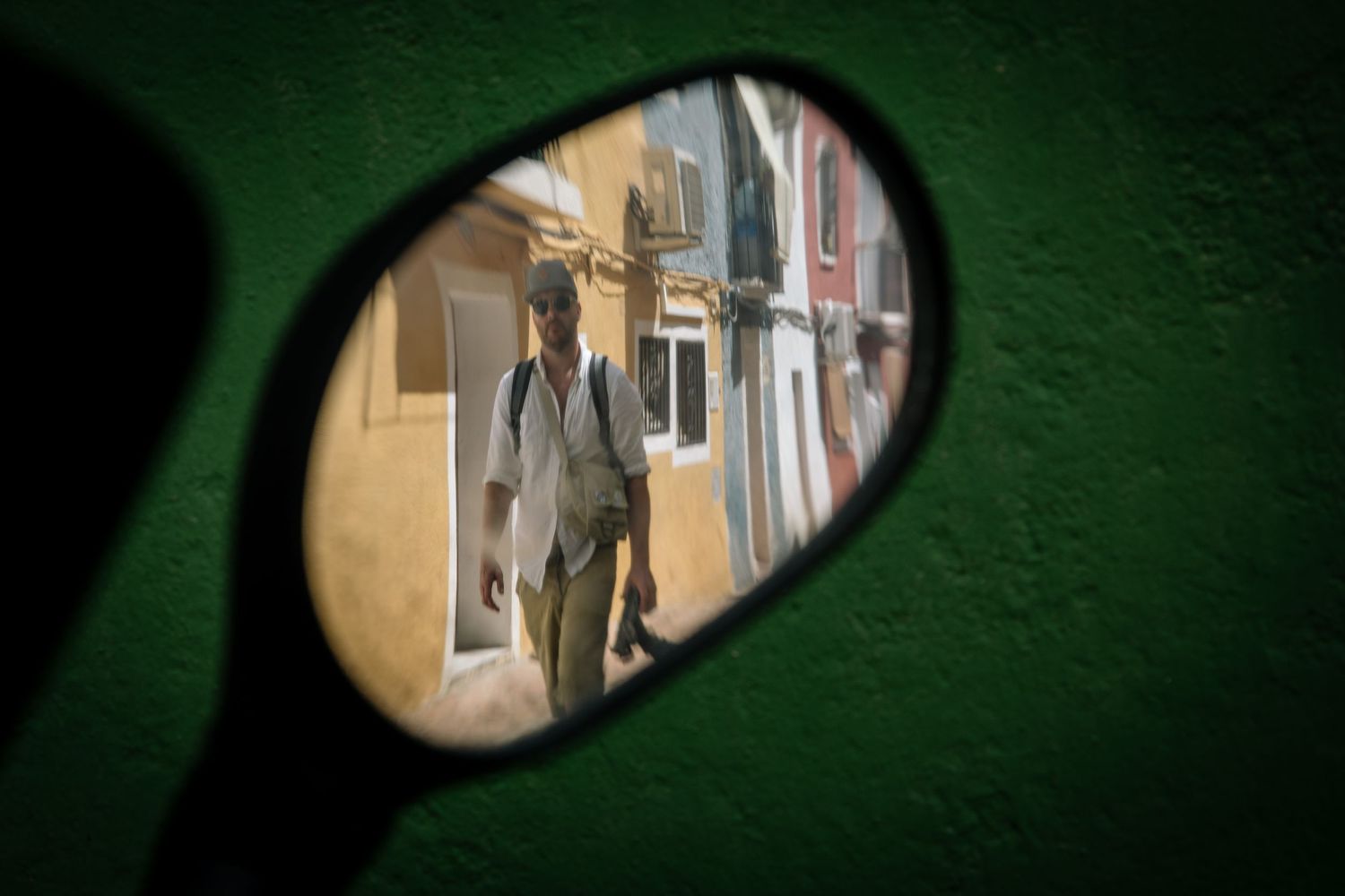 Mirror reflection view of street scene through rounded side view mirror.