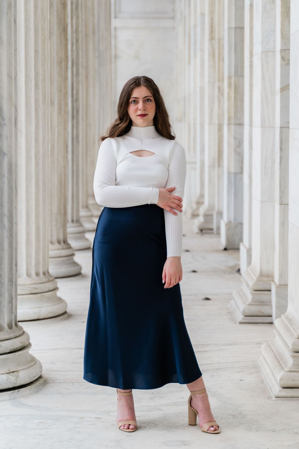 Stylish winter outfit captured in an architectural setting with white columns and natural lighting.