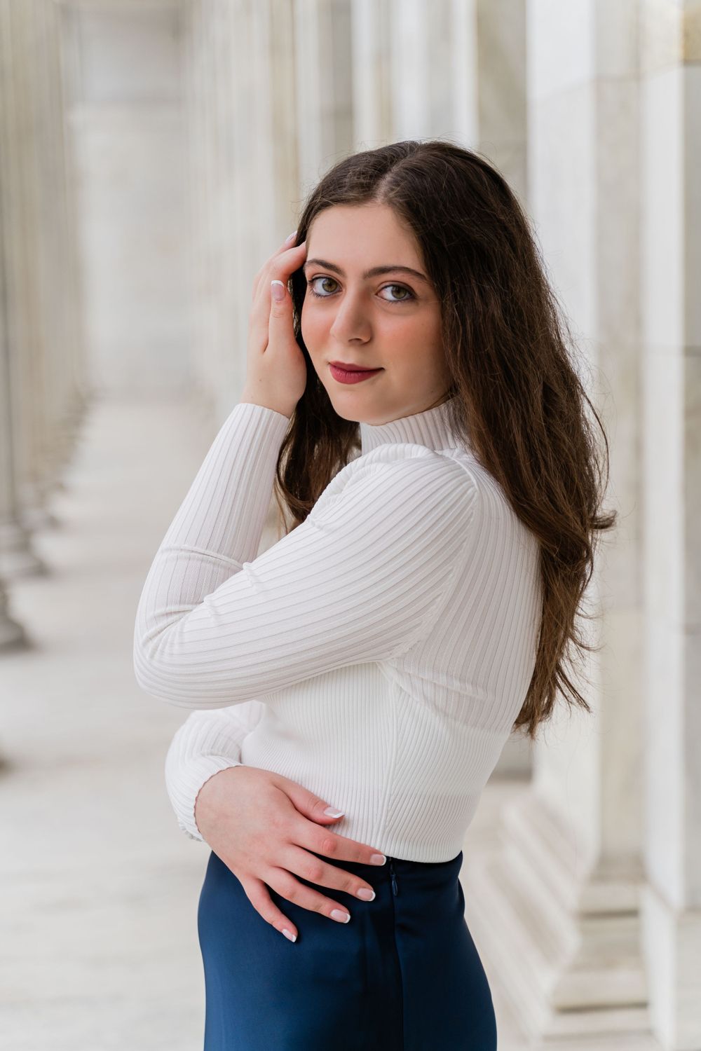 Artistic portrait with soft lighting highlighting a winter fashion look against white columns.