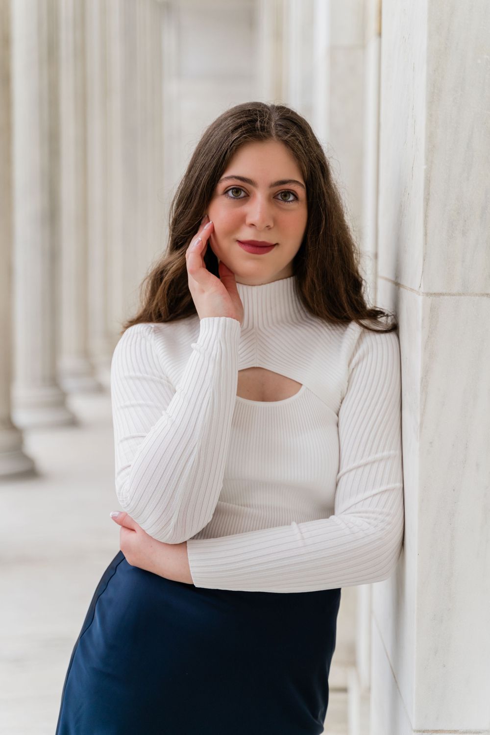 Fashion portrait showcasing a white cutout sweater against a backdrop of classical white columns.
