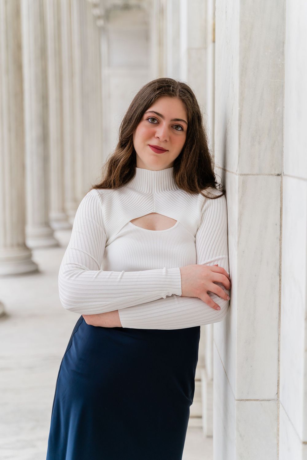 Modern fashion photography featuring a white turtleneck with cutout detail against classical architecture.