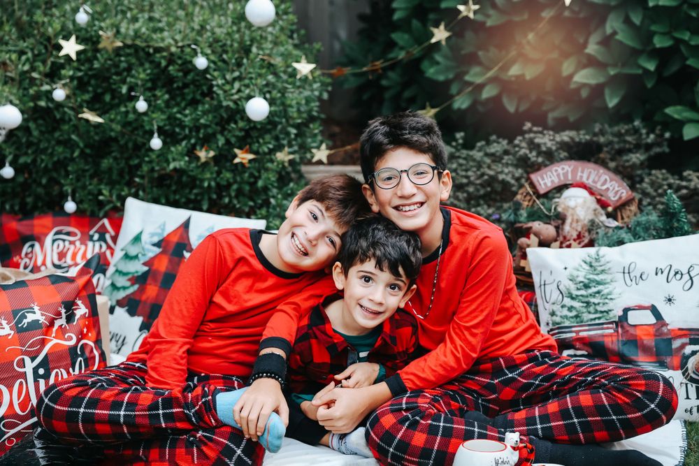 A cozy Christmas photo scene with matching red outfits and plaid decor against a garden backdrop.
