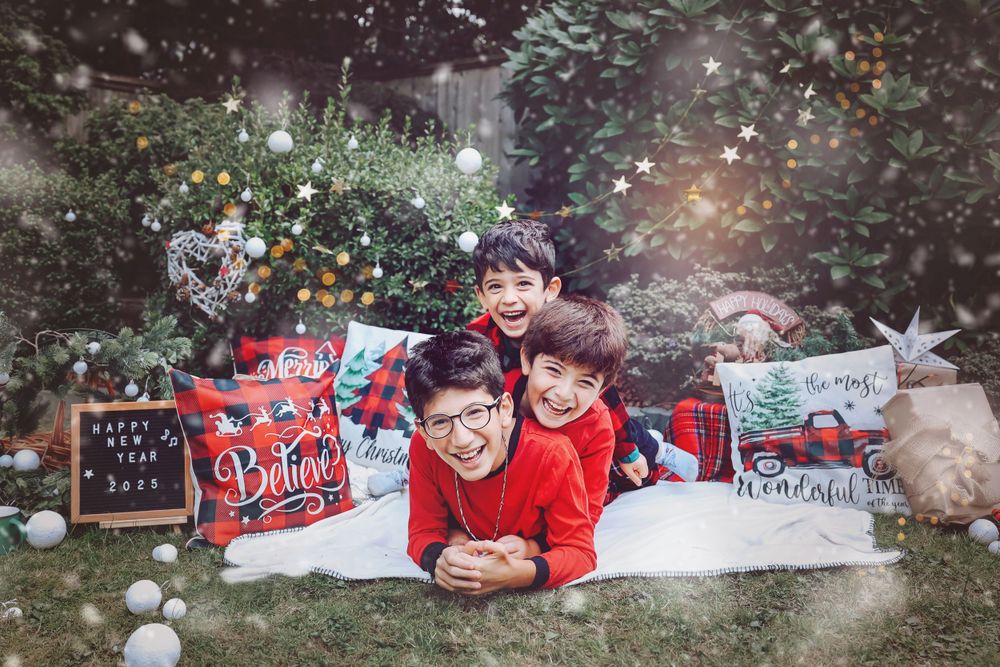 A playful holiday photo setup with red clothing and Christmas decorations on a white blanket outdoors.