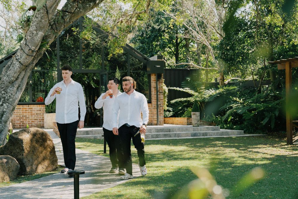 Group walking along garden path surrounded by lush greenery and trees.